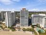 High-rise residential building featuring expansive glass balcony railings, a flat roofline, and direct sandy beach access