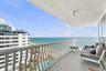 Covered balcony with white metal serpentine railing, concrete flooring, and unobstructed water scenery