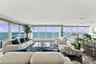 Open-concept living space featuring floor-to-ceiling glass wall panels, wood-finish flooring, recessed lighting, and a kitchen island with pendant lig