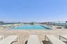 Rooftop swimming pool featuring large-format tile decking, metal perimeter fencing, and stainless steel pool ladders