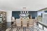 Dining area featuring dark textured wall treatment, large-format polished flooring, built-in shelving unit, linear pendant lighting, and floor-to-ceil