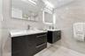 Dual floating vanities featuring dark-toned textured cabinetry, white integrated sinks, polished chrome fixtures, and full-wall porcelain tiling
