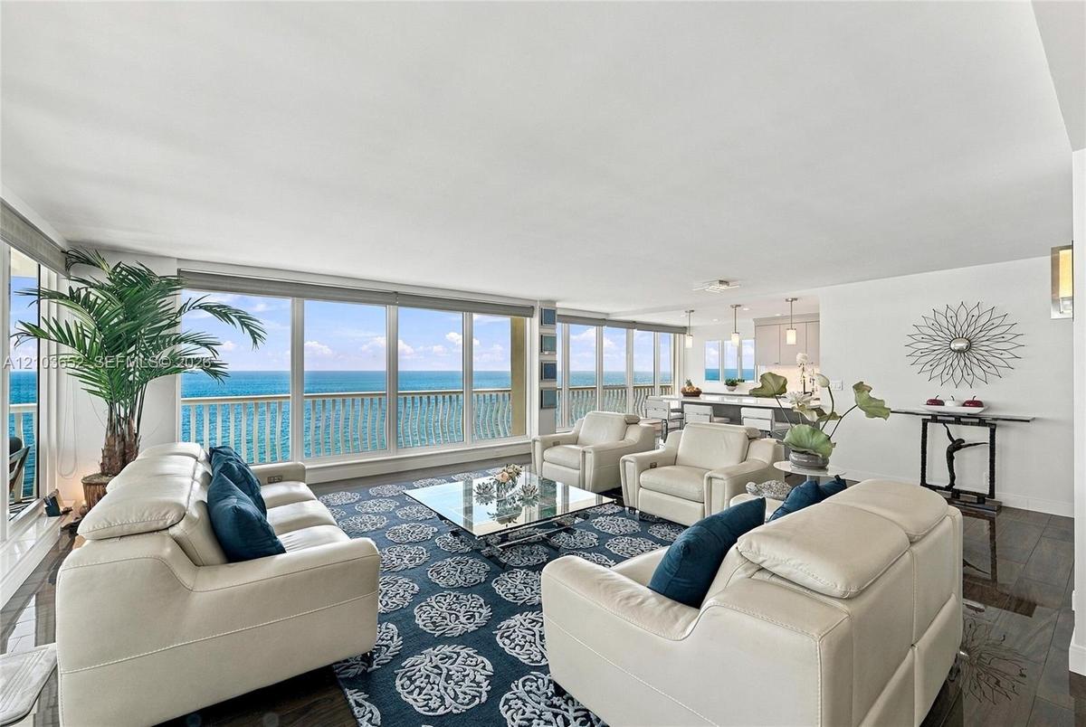 Floor-to-ceiling windows featuring ocean scenery, wood-finish flooring, and recessed ceiling lighting