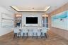 Custom millwork wall unit with built-in cabinetry and display shelving, integrated wet bar with sink, tiered tray ceiling with recessed lighting, and 