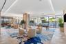 Expansive open-concept space featuring herringbone-patterned wood-finish flooring, floor-to-ceiling glass paneling, recessed cove lighting, and floor-