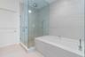 Walk-in glass-enclosed shower featuring a rainfall showerhead, integrated tiled wall niche, deep soaking tub with deck-mounted faucet, and large-forma
