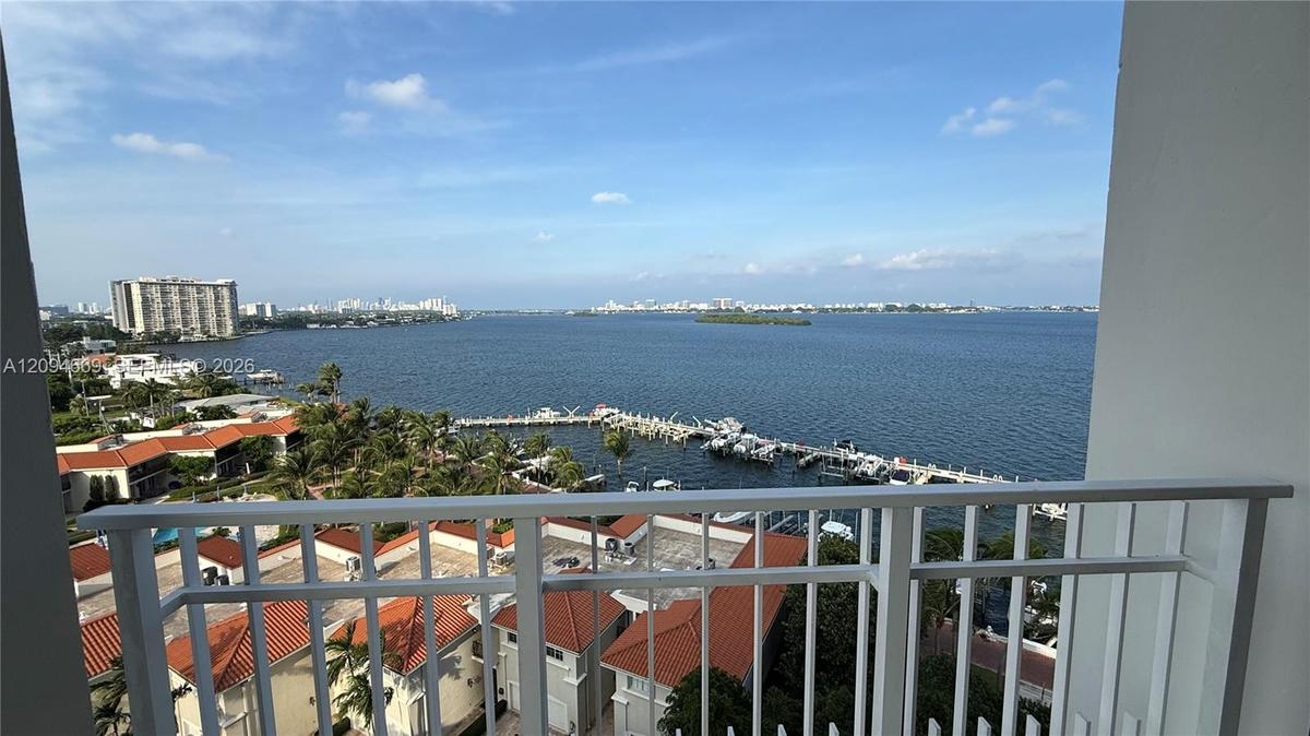 Covered balcony with white metal railings overlooking a coastal waterway and marina