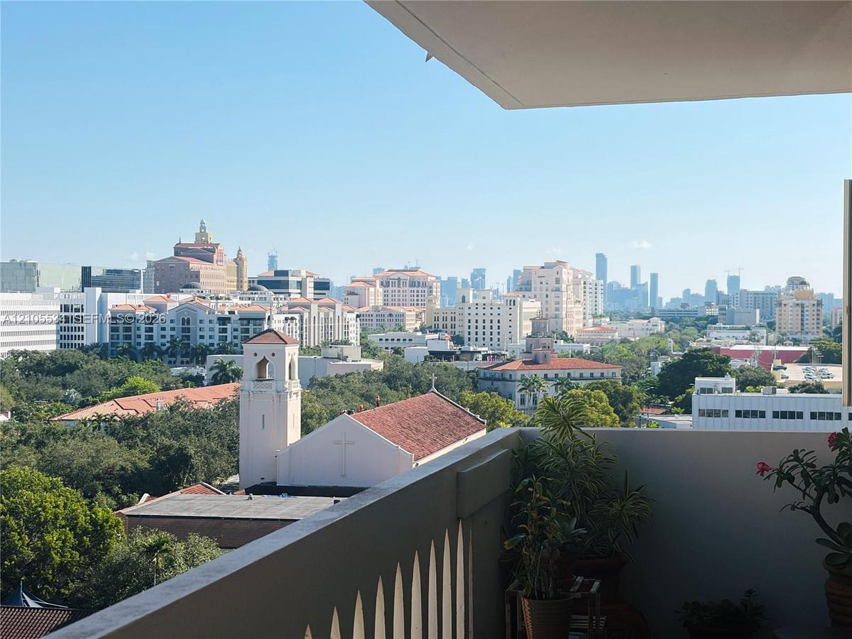 Covered balcony featuring a solid masonry perimeter wall and metal railing overlooking a cityscape