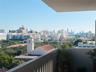 Covered balcony featuring a solid masonry perimeter wall and metal railing overlooking a cityscape