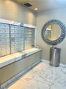 Walk-in shower featuring a frameless glass enclosure, recessed wall niche, wall-mounted shower head, and stone-tile flooring