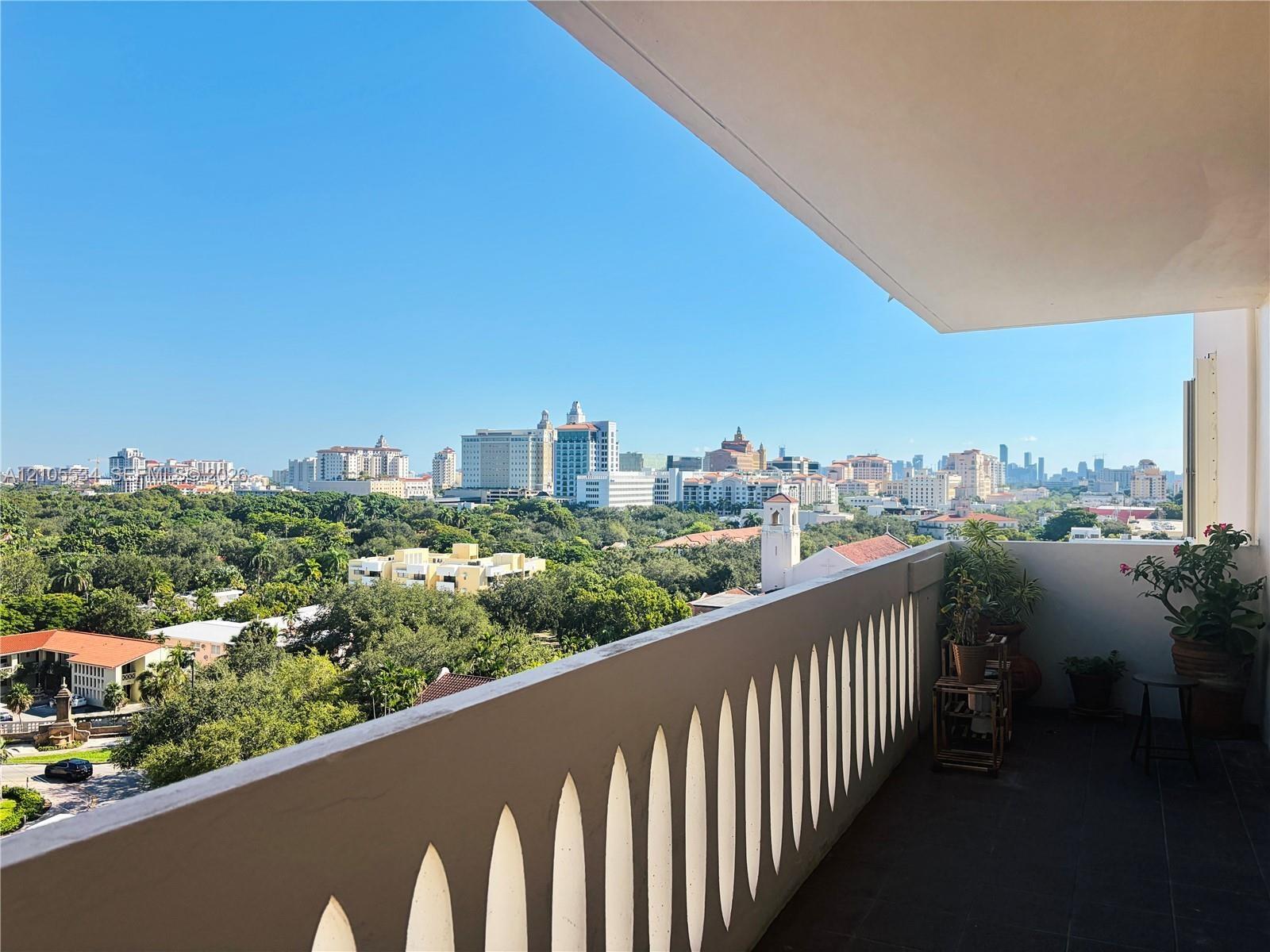 Covered balcony featuring a decorative arched railing, tile flooring, and urban skyline scenery
