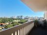 Covered balcony featuring a decorative arched railing, tile flooring, and urban skyline scenery