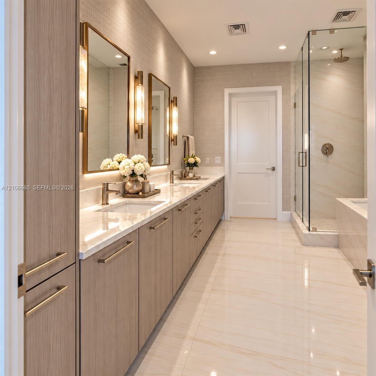 Dual-sink vanity with light-tone wood cabinetry, stone-finish countertops, brass-finish wall-mounted lighting, and a glass-enclosed walk-in shower