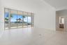 Floor-to-ceiling glass wall with sliding doors, large-format tile flooring, recessed ceiling lighting, and exterior balcony