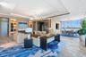 Expansive living area featuring a tray ceiling, integrated custom shelving with built-in accent lighting, a linear fireplace, wood-finish herringbone 