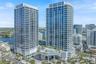 High-rise residential towers featuring floor-to-ceiling glass paneling, wrap-around balconies, an elevated podium pool deck, and structured covered en