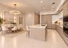 Kitchen featuring light wood-finish cabinetry, a large central island with light-toned countertops, integrated stainless steel appliances, recessed li