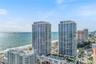 High-rise residential towers featuring glass-curtain wall facades, exterior balcony systems, and a multi-level podium deck with a pool