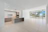 Open-concept kitchen featuring two-toned cabinetry, a stone-surface island, built-in double ovens, recessed lighting, and expansive floor-to-ceiling g