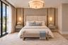 Room featuring floor-to-ceiling windows, dual built-in floating bedside consoles, custom gold-accented wall paneling, pendant lighting, and a tiered c