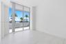 Floor-to-ceiling glass panel windows, large-format tile flooring, and integrated sliding glass door providing access to a balcony with a glass railing