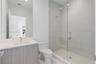 Bathroom featuring a vanity with a white countertop and rectangular undermount sink, a frameless glass-enclosed shower with floor-to-ceiling tile, and