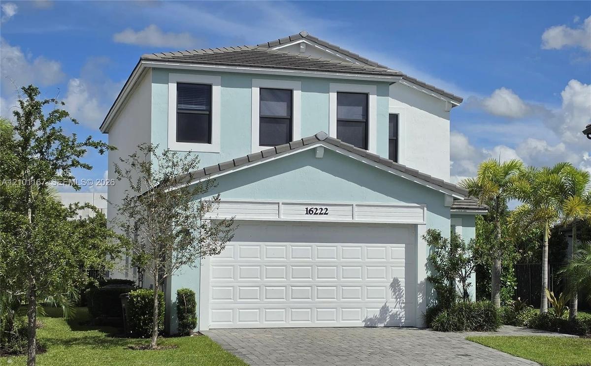 Two-story exterior featuring light-toned stucco siding, a tiled roof, a multi-panel garage door, and a paved driveway