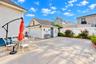 Concrete patio space featuring a detached garage, white vinyl fencing, and established perimeter landscaping