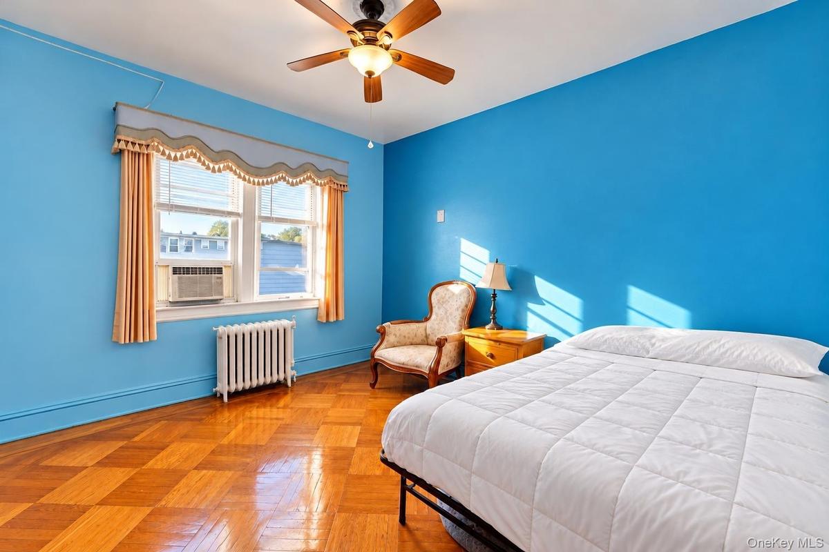 Parquet wood-finish flooring, ceiling fan with integrated lighting, and multi-pane window