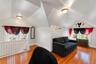Vaulted ceiling space featuring wood-finish flooring, a metal radiator, and a white wooden staircase railing