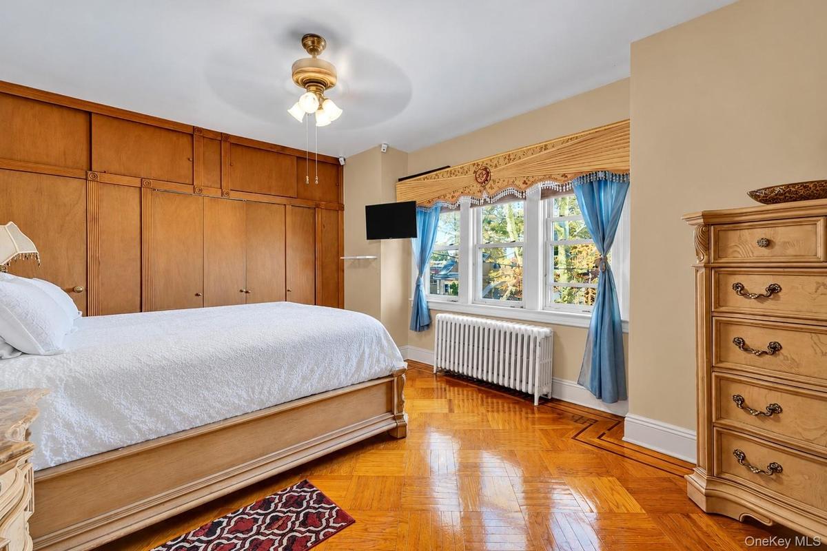 Wall-to-wall built-in wood cabinetry, parquet flooring, triple-pane window configuration, and an integrated ceiling fan with multi-light fixture