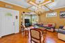 Living area featuring parquet wood flooring, coffered ceiling with a crystal chandelier, arched architectural columns, and leaded glass windows