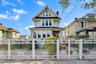 Two-story residence featuring horizontal siding, a gabled roofline, a front porch, and a decorative white metal privacy fence