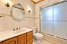 Bathroom featuring a wood vanity with a solid-surface countertop, integrated basin, dual-handled metallic faucet, decorative tile surround, and a tub-
