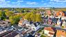 Aerial perspective of a residential neighborhood featuring mature tree-lined streets, diverse architectural styles, and proximity to regional infrastr