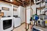 Utility space featuring tile flooring, exposed ceiling joists, and a six-panel door
