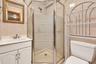 Bathroom featuring a corner shower with glass enclosure, white vanity cabinet, solid-surface countertop with integrated sink, and ceramic wall tiling