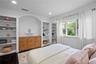 Built-in cabinetry with wood-grain finish, recessed shelving, arched architectural alcove, dark wood-finish flooring, and multi-pane window