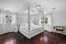 Wood-finish flooring, dual windows with curtain rods, and a ceiling-mounted light fixture