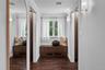 Hardwood-style flooring, built-in wooden cabinetry, arched wall mirror, wall-mounted sconce lighting, and crown molding
