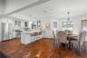Kitchen featuring wood-finish flooring, white cabinetry, stone-surfaced kitchen island, stainless steel appliances, and multi-light hanging fixtures