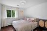 Bedroom featuring wood-finish flooring, a large sliding window, and a decorative semi-flush mount ceiling fixture