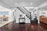 Staircase featuring dark-stained wood treads, matching handrail, and white risers, complemented by deep-toned hardwood flooring and recessed lighting
