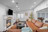 Fireplace with stone-tile surround, mantel, and architectural columns, complemented by recessed lighting, wood-finish flooring, and windows with integ
