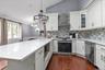 Kitchen featuring white cabinetry, solid-surface countertops, wood-finish flooring, stainless steel appliances, and a multi-tonal tile backsplash