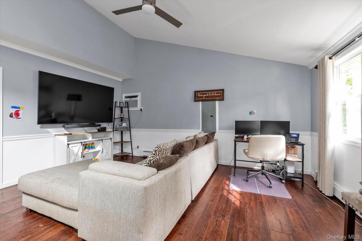 Vaulted ceilings, wood-finish flooring, two-tone walls with chair rail molding, and a ceiling fan