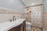Bathroom featuring a dark wood vanity with an integrated basin, bronze-finish hardware, ceramic wall tiling with decorative floral inlay, and a built-