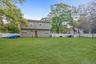 Expansive backyard featuring a level lawn, mature trees, and a white privacy fence
