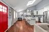 Vaulted ceilings with a skylight, wood-finish flooring, shaker-style cabinetry, solid-surface countertops, and a decorative tile backsplash
