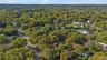 Aerial perspective of a lot featuring mature trees, wooded surroundings, and direct road access